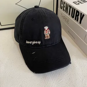 Detail of bear embroidery and 'never give up' text on distressed black baseball cap