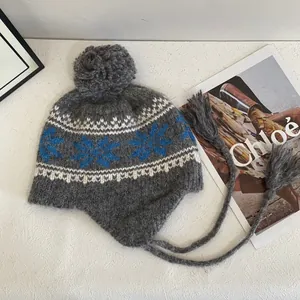 Winter Fair Isle knit trapper hat with blue snowflake patterns and grey pom-pom