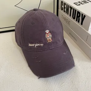 Detail of cartoon bear embroidery and distressed brim on purple cotton baseball cap