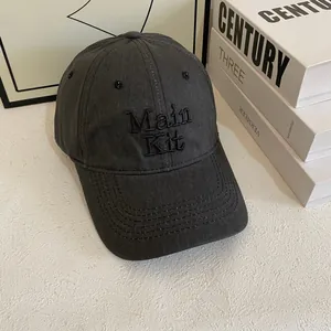 Dettaglio del ricamo Main Kit su cappellino da baseball in tela grigio scuro con occhielli