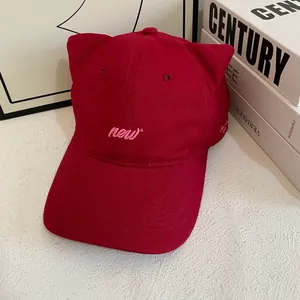 Detail view of a dark red cat ear baseball cap with pink embroidery and cotton texture