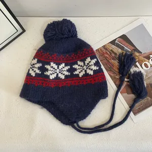 Close-up of winter knit trapper hat with snowflake patterns, pompoms and long tassels