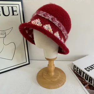 Detail of burgundy plush knit bucket hat with bohemian crochet trim and colorful woven band