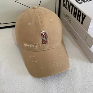Detailed close-up of khaki baseball cap featuring bear embroidery and distressed brim