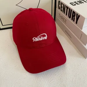 Close-up of white Rainbow embroidery on red cotton twill baseball cap with stitching