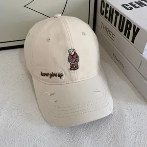 Detail of cream baseball cap featuring bear embroidery and never give up label