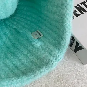 Macro detail of mint green chunky knit beanie showing soft texture and logo label