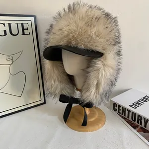 Dettaglio del cappello invernale in pelliccia sintetica con tesa in pelle nera e fiocco