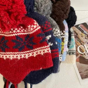 Detail of knitted winter beanies featuring Nordic snowflake patterns and large pom-poms