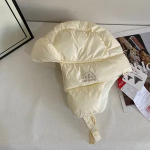 Dettaglio del cappello aviatore trapuntato crema con ricamo montagna e fodera in pile