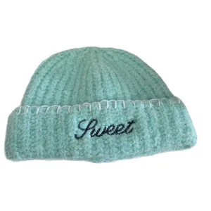 Mint green knit beanie featuring sweet embroidery and white decorative stitching details