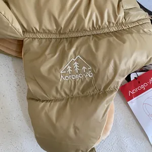 Dettaglio del cappello invernale trapuntato kaki con fodera in pile e ricamo bianco