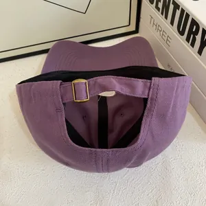 Detail of purple cotton baseball cap featuring adjustable vintage gold metal buckle closure