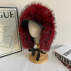 Dettaglio del cappello invernale in ecopelliccia rossa con visiera in pelle e fiocco nero