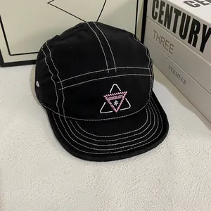 Detailansicht der Kontrastnähte und rosa Stickerei auf einer schwarzen 5-Panel-Kappe