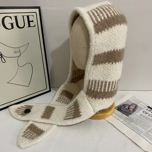 Détail de la cagoule en tricot rayé avec bouton noir et texture de laine douce épaisse