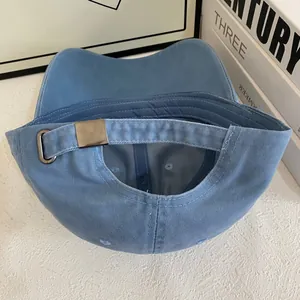 Detail of adjustable metal buckle and stitching on light blue cotton baseball cap