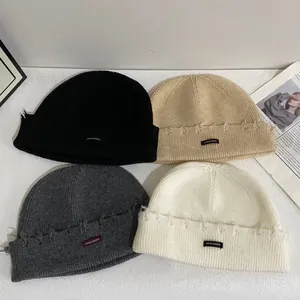 Gorros de punto desgastados en cuatro colores con detalles rotos y etiqueta textil