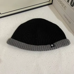 Detail of two-tone ribbed knit beanie with snowflake patch and gray folded cuff