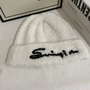 Primer plano de gorro de punto blanco con bordado negro en tela suave y gruesa