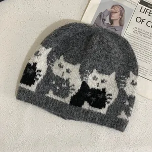 Close-up of grey knitted beanie featuring cat jacquard pattern and fuzzy mohair texture