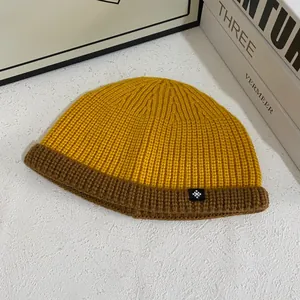 Detail of yellow and brown contrast ribbed knit beanie with a snowflake patch accent