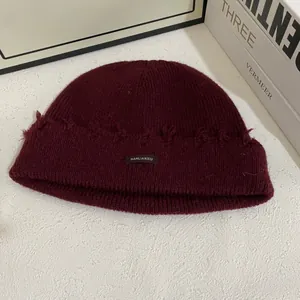 Gorro de punto granate con detalles desgastados vintage y etiqueta sobre fondo blanco