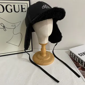 Detail of black winter trapper hat with warm fleece lining and mountain logo on mannequin