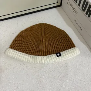 Detail view of contrast knit beanie with brown and cream textures and snowflake patch
