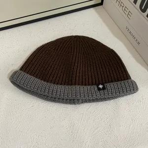 Close-up of a two-tone knit beanie with grey cuff and snowflake patch detail