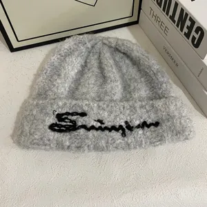 Detalle del gorro de punto gris con textura de felpa suave y bordado cursivo