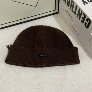 Detalle del gorro de punto acanalado marrón oscuro con agujeros vintage y etiqueta tejida
