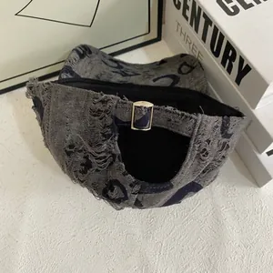 Detail view of distressed grey denim baseball cap featuring worn edges and metal buckle