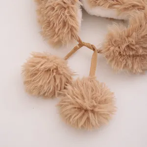 Dettaglio del cappello invernale in peluche marrone con pompon e calda fodera bianca