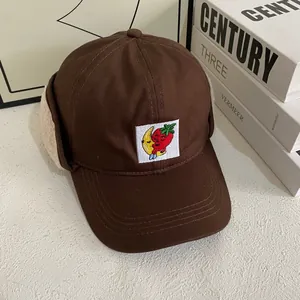 Detailed view of dark brown ear flap baseball cap with soft faux lamb wool lining and embroidery