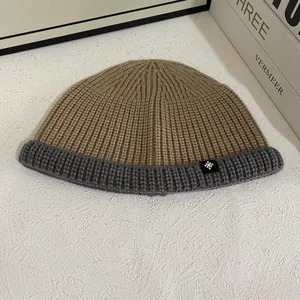 Close-up of ribbed knit texture on two-tone camel and grey beanie with snowflake tag