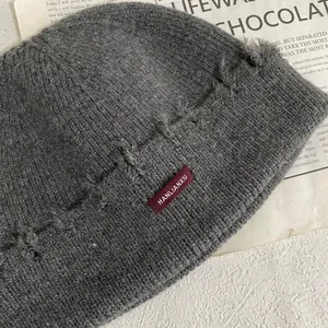 Primer plano del gorro de punto gris oscuro con etiqueta roja y detalles desgastados