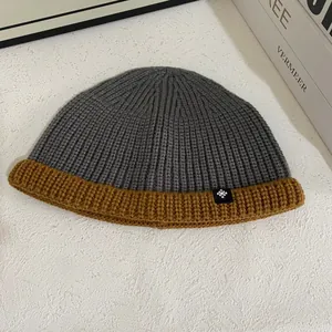 Close-up of contrast knit beanie with grey body, brown cuff and snowflake logo detail