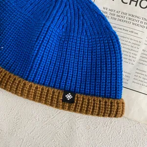 Detail of blue and brown knit beanie showing thick texture and snowflake square patch