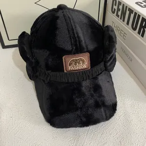 Detail of black plush baseball hat featuring a leather patch with fashion embroidery