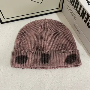 Détail du bonnet en maille tie-dye rose avec trous vieillis et texture côtelée épaisse
