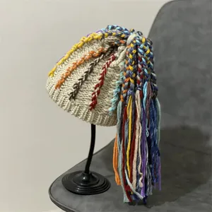 Detail of bohemian knit beanie with colorful handmade braids and tassels on a stand