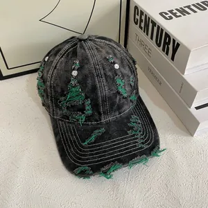 Close-up of distressed denim baseball cap with green frayed edges and white contrast stitching