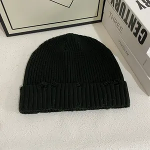 Détails du bonnet en maille côtelée noire avec des bords déchirés et un effet usé