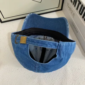 Detail of blue denim baseball cap showing adjustable strap and bronze metal buckle