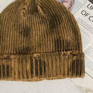 Gros plan du bonnet en maille vieillie avec bords déchirés et texture rayée