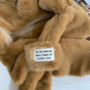 Close-up of caramel plush hood texture with white embroidered motivational label