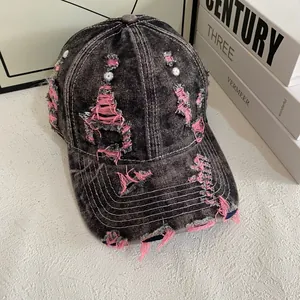 Detail of distressed denim baseball cap featuring unique ripped fabric and pink stitching