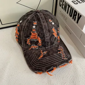 Detail of distressed denim baseball cap with orange contrast stitching and frayed edges