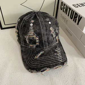 Detail of distressed grey denim baseball cap with frayed holes and contrast stitching